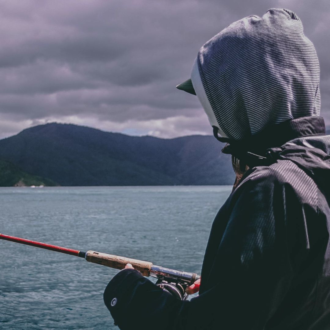 Person fishing on a lake with mountains in the background