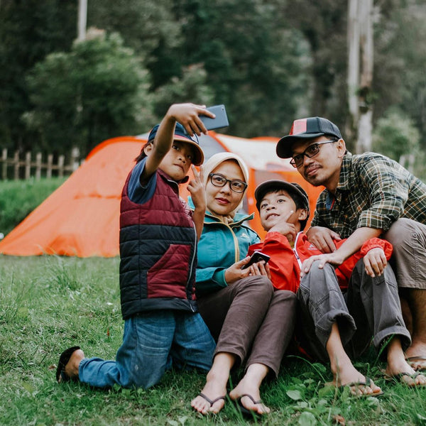 Family taking a selfie outdoors with an orange tent in the background